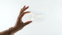 Hand holding glowing light bulb with filament against white background representing innovation creativity and bright ideas for business concepts.
