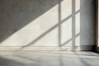Sunlight casting geometric window shadows on minimalist white wall and marble floor in empty room, creating architectural contrast and depth.
