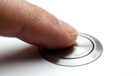 Finger pressing a metallic circular button isolated on white background, ready for web design, user interface, and application graphics.