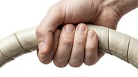 Hand gripping a beige leather steering wheel, close-up shot showing knuckles and fingers, isolated on white background.