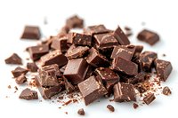 Broken dark chocolate pieces and crumbs scattered on white background, macro food photography showing rich texture and glossy surface of confectionery.