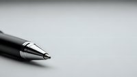 Close-up of elegant black fountain pen with silver nib on clean white surface, minimalist office supplies for professional writing and signing documents.