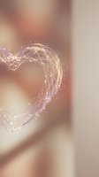 Abstract glowing heart shape made of flowing light trails and particles on soft blurred background for romantic designs and Valentine's Day concepts.