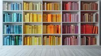 Colorful rainbow bookshelf with books arranged by color from blue to red on white wooden shelves against white wall, gray wooden floor in modern interior.