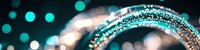 Glowing turquoise bokeh lights and sparkling silver glitter create magical abstract background with blurred circular shapes and shimmering particles.