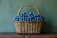 Fresh blueberries in wicker basket on wooden table against green background for healthy eating and organic food concepts.