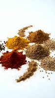 Colorful aromatic spices and seasonings scattered on white background for culinary cooking and food preparation projects.