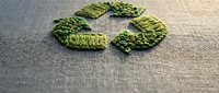 Green embroidered recycling symbol on natural linen fabric representing eco-friendly sustainability and environmental consciousness for Earth Day campaigns.