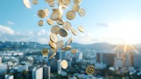 Golden coins falling over cityscape with sunset and mountains in background, symbolizing wealth, financial success and urban economy growth period.