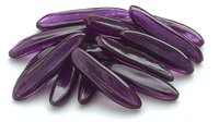 Purple elongated glass beads with glossy surface scattered on white background, suitable for jewelry making and craft projects. Isolated macro shot.