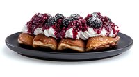 Fresh berry waffles topped with whipped cream, blackberries and raspberries served on black plate against white background, isolated food photography.