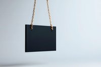 Black rectangular sign hanging on golden chain against white background, minimalist mockup for branding and design presentation on isolated backdrop.