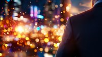 Silhouette of person against vibrant city bokeh lights at night, creating atmospheric urban scene with glowing orange and blue defocused background.