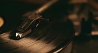 Vintage turntable needle on spinning vinyl record with warm lighting creating nostalgic atmosphere for music and audio production projects.