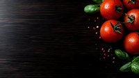 Fresh ripe tomatoes with water drops and basil leaves on dark wooden background with copy space. Food photography for restaurant menu.