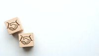Wooden blocks with handshake symbols representing business partnership, teamwork and cooperation concepts on white background with copy space.