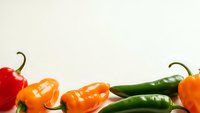 Fresh colorful hot peppers arranged on white background with copy space for culinary and cooking projects.