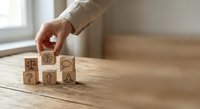 Business person arranging wooden blocks with strategy icons on desk for planning and decision making concepts in modern office environment.