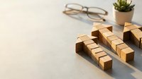 Wooden blocks arranged in rows on desk with glasses and plant creating organized workspace for business planning and strategy development.