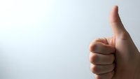 Hand showing thumbs up gesture against clean white background expressing approval, success, and positive feedback for business presentations.