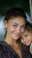 Young mixed race mother and daughter share tender moment outdoors, both wearing floral print clothing and genuine smiles, expressing family love and bonding.