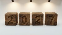 Wooden blocks displaying 2027 numbers arranged on white surface with modern pendant lighting for business planning and future goals.
