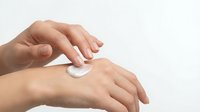 Woman applying white cream or lotion to hand for skincare, cosmetics, and beauty treatment on isolated background.