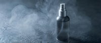 Spray bottle with mist effect on dark textured surface, suitable for cosmetics, perfume, cleaning product packaging and advertising campaigns.