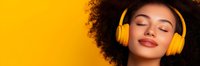 Young African American woman with curly hair wearing bright yellow headphones enjoying music with eyes closed against vibrant yellow background for lifestyle content.