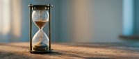 Vintage brass hourglass with golden sand flowing through glass bulbs on wooden surface with soft natural lighting for time management concepts.