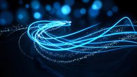 Glowing cyan light trails and particle streams flowing across dark background, representing data flow, digital transformation, technology innovation, and futuristic connectivity concepts.