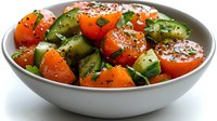 Fresh cucumber and cherry tomato salad with herbs and spices in white ceramic bowl, healthy Mediterranean appetizer on light background.