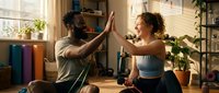 Couple giving high five during home workout session, celebrating fitness achievement together in living room with plants and equipment.
