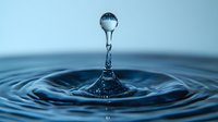 Water drop splash creating crown shape with sphere droplet suspended above rippling circles on blue surface, captured in high-speed macro photography.