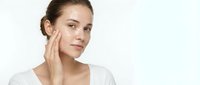 Young Caucasian woman applying skincare cream to face with gentle touch, natural beauty routine and facial care concept for cosmetic advertising.