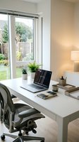 Modern home office workspace with white desk, ergonomic chair, laptop, and potted plants near large garden window with natural daylight for remote work and productivity.