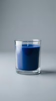 Blue scented candle in clear glass holder on neutral background for home decor and relaxation concepts.