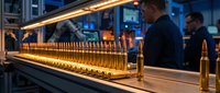 Brass ammunition bullets lined up on industrial production conveyor belt in modern manufacturing facility with workers monitoring quality control process.