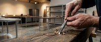 Skilled craftsman hands carving intricate details into weathered wood using traditional chisel tool in modern workshop studio for artisan woodworking projects.