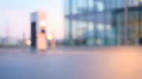 Modern urban plaza at dusk with blurred contemporary architecture, glass buildings, and soft golden lighting creating an abstract cityscape atmosphere for corporate and commercial design projects.