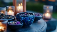 Aromatic dried herbs and flowers in blue ceramic bowls with glowing candles creating magical atmosphere for spa, meditation, and wellness rituals at dusk.