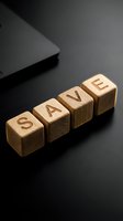 Wooden cubes spelling SAVE on a dark surface near a laptop, symbolizing financial planning, budgeting, and money management concepts.