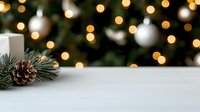 Festive winter scene with white table surface, pine cone, evergreen branch and blurred Christmas tree lights creating magical bokeh background.