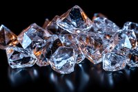 Clear crystal chunks with orange light reflections on black background, macro photography showing transparent mineral structure and facets. Luxury gemstone concept.