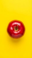 Shiny red apple isolated on bright yellow background, perfect for food and nutrition design projects.