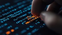 Finger pointing at digital data on computer screen with glowing orange and blue numbers, binary code and financial market data in dark background.