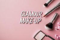 Professional makeup brushes and cosmetic products arranged on pink background with white glamour makeup text overlay for beauty industry marketing.