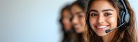 Young diverse female customer service representative wearing headset smiling at camera with multicultural team colleagues in background at call center.