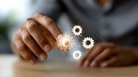 African American businessman touching glowing digital gears, representing business automation, innovation and technological solutions in modern workplace setting.
