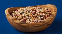 Assorted legumes and beans in wooden bowl on blue background. Mixed pulses including lentils, chickpeas, kidney beans for healthy cooking and nutrition.